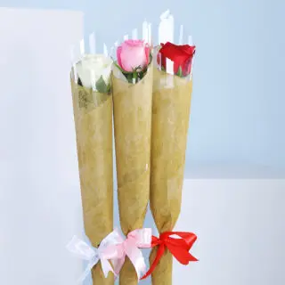 Three wrapped bouquets with pink, white, and red roses, tied with coloured ribbons against a blue background.
