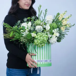 A flower box with lush hydrangeas, white roses, green chrysanthemums, calla lilies, and eryngium, finished with fresh greens.