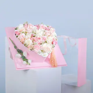 Heart-shaped pink box filled with white and pink ohara roses, white lisianthus, pink and white hydrangea, and amaranthus.