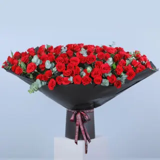 Funnel Shape Red Rose bouquet with eucalyptus leaves wrapped in black and tied with pink ribbon