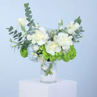 White hydrangea with greens in a glass vase