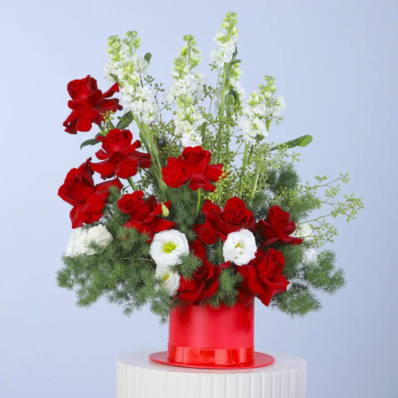 Click to enlarge image Bouquet of red roses, mathiolla, white lisianthus, and greenery arranged in a red hat box