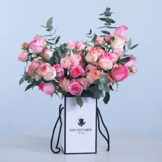 Box of pink roses, Jumelia roses, baby roses, and fresh leaves.