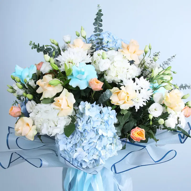 02 - Ethereal Blue & Peach Floral Symphony Ethereal floral arrangement with hydrangeas, roses, chrysanthemums, and lisianthus.