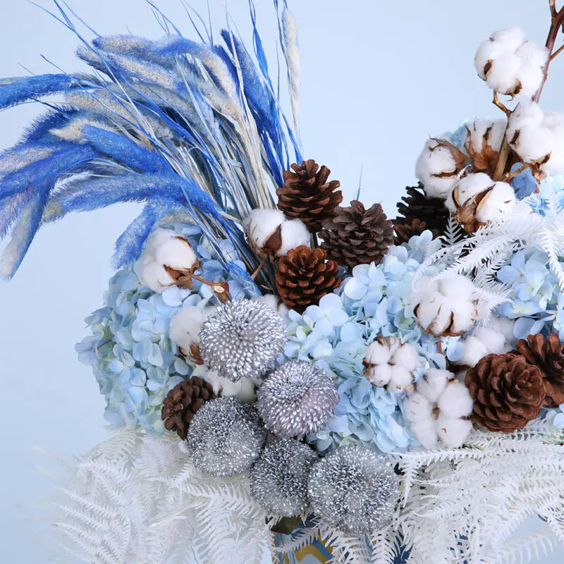 03 - Vibrant Blue Centerpiece Flower arrangement showcasing blue hydrangeas, pine cones, cotton, and ping pong balls with dry feathers.