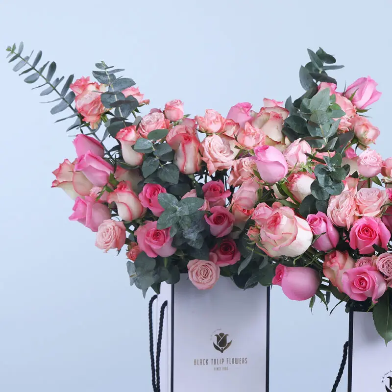 03 - Floral Rose Combo Close-up of a vibrant 60-rose arrangement with eucalyptus, showcasing pink, Jumelia, and baby roses in a decorative box.