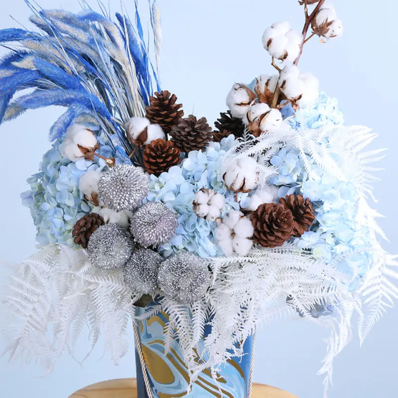 05 - Vibrant Blue Centerpiece Flower arrangement showcasing blue hydrangeas, pine cones, cotton, and ping pong balls with dry feathers.