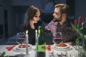 A couple sharing a romantic dinner at home, adorned with elegant tableware, surrounded by candlelight, and a romantic ambiance for a cozy evening.