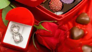Beautiful Traditional Valentine's Day gifts consisting of a Dazzling earring piece, a lavish red rose, and some heart-shaped Choco treats.