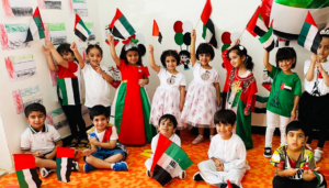 A group of students holding the flag of the United Arab Emirates, a horizontal tricolor of green, white, and black with a vertical red bar at the hoist