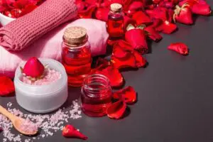 natural spa concept with fresh roses petals rose sea salt essential oil soft towels modern hard light dark shadow black stone concrete background copy space