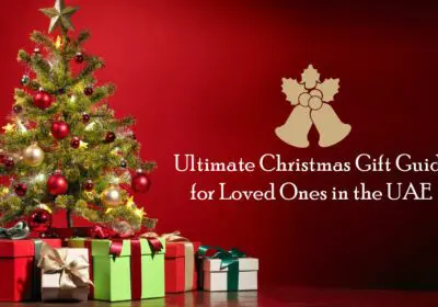 A beautifully decorated Christmas tree with colorful ornaments, surrounded by wrapped gifts. The text "Ultimate Christmas Gift Guide for Loved Ones in the UAE" is displayed above the image.