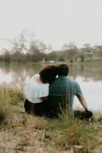 A couple sitting by a lake in the countryside.