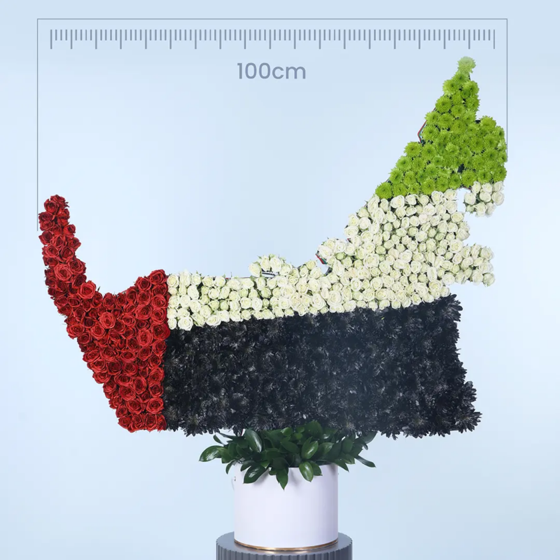 uae-map-national-day-flower-gift A floral arrangement in the shape of the UAE map, featuring white, red, black, and green flowers.