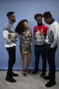 A group of friends posing for a photo at a Christmas party, all wearing festive and quirky Christmas sweaters.