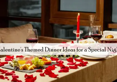 A Valentine's Day dinner table set for two. The table is decorated with red rose petals, lit candles, and glasses of red wine. There's a variety of food on the table, including cheese, grapes, and chocolates. The text "Valentine's Themed Dinner Ideas for a Special Night" is displayed across the image.