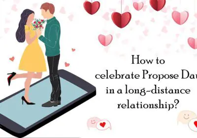 A couple on a video call, smiling and holding up cards with messages of love. The background shows heart-shaped balloons and decorations.