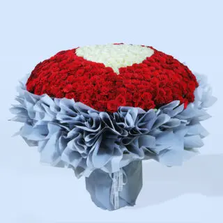 A large, luxurious bouquet of red roses with heart made of white roses at the centre.