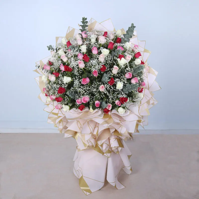 A grand, luxurious bouquet of red, white, pink roses, and greenery.
