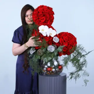 Festive fish bowl arrangement with 110 roses, orchids, and Christmas decorations.