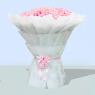 A large bouquet of 100 pink roses, wrapped in white paper with a pink ribbon, standing on a wheeled stand.