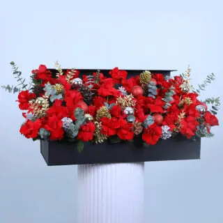 Christmas flower arrangement with red roses and pine cones.