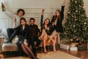 Friends relax on a couch adorned with Christmas decorations, enjoying a festive gathering in preparation for New Year's 2025.
