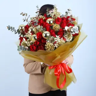 Golden sprayed pinecones, red roses, and eucalyptus bouquet wrapped in gold paper