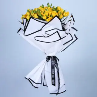 Bouquet of yellow roses wrapped in black and white paper.