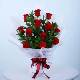 Valentines Day Home 32 A bouquet of 12 red roses with leaves wrapped in white tied with a maroon ribbon.