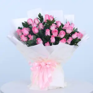 A bouquet of light pink roses wrapped in white paper with a pink ribbon.