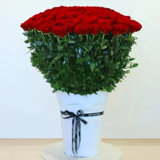 365 red roses in a white wrap tied with green leaves and tied with a black ribbon.