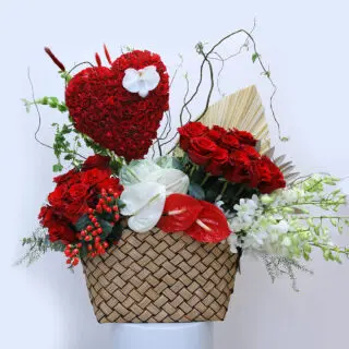 Romantic Valentine's Day floral arrangement: a heart of red roses in a basket, complemented by white flowers and greenery.