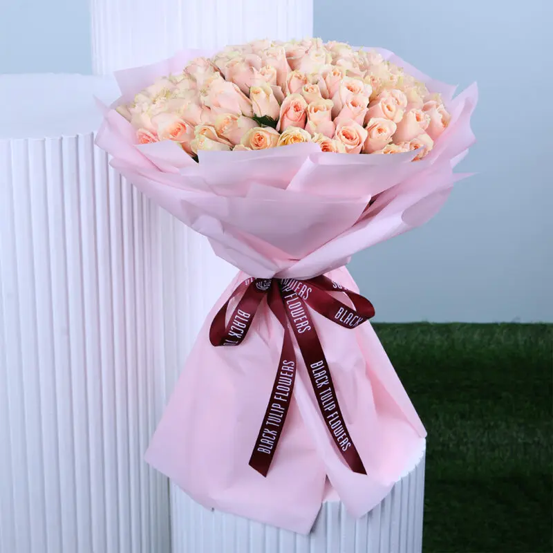 feminine-rose-bouquet An elegant Women’s Day bouquet featuring fresh peach roses wrapped in blush pink paper and tied with a maroon ribbon.