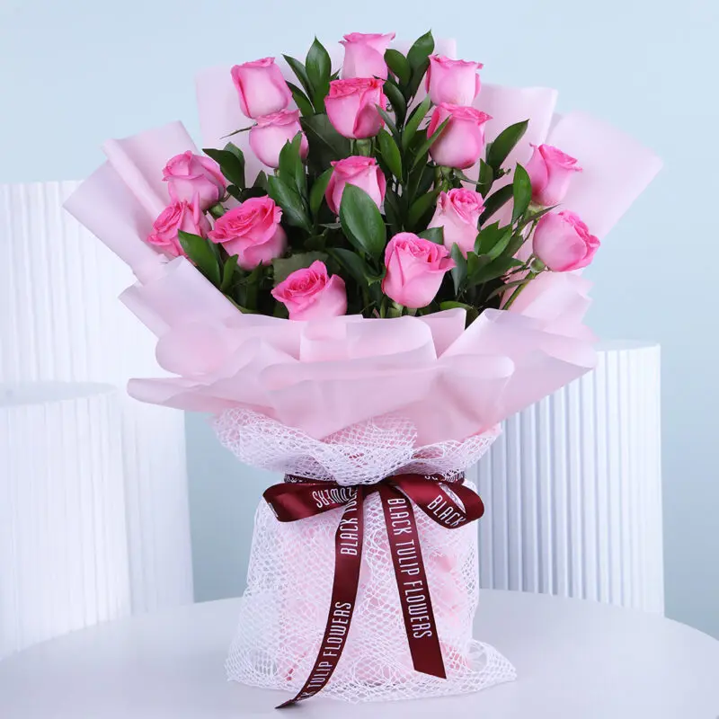 baby-pink-bouquet A delicate bouquet of soft pink roses, carefully arranged in light pink wrap, displayed on a white table.