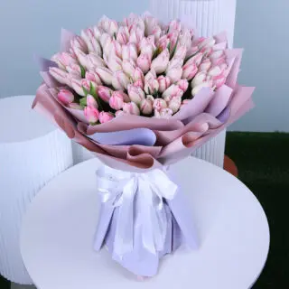 Pink tulips bouquet, wrapped in light purple and tied with a white satin bow.