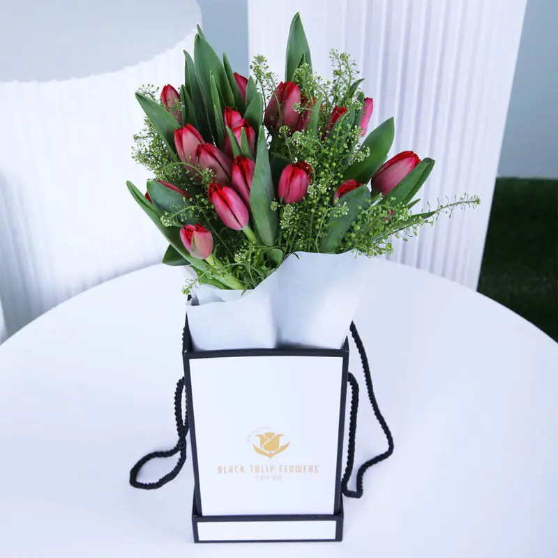 A delightful pink tulip box, elegantly wrapped in white with a luxurious gift bag.