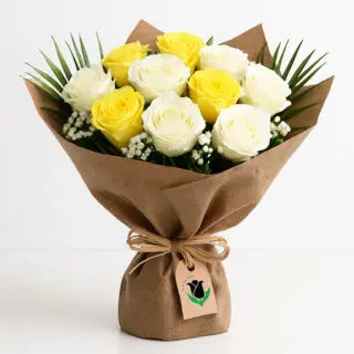 A bouquet featuring yellow and white roses, complemented by white gypsophila and green leaves, all wrapped in brown paper.