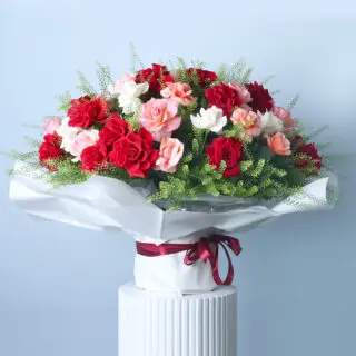 BTF Home 35 A vibrant bouquet featuring a mix of red, pink, and white roses accented with delicate white lepidium, wrapped in white and tied with a burgundy ribbon.