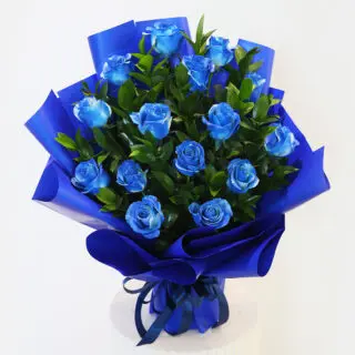 A graduation garland made of blue and white flowers with greenery with a small black graduation cap with the word "Congratulations!"