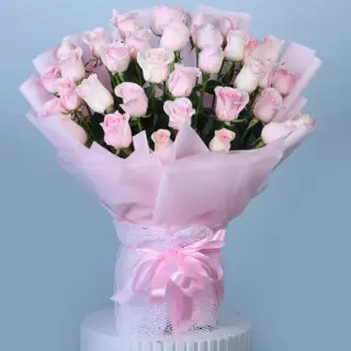 A beautiful bouquet of soft pink roses wrapped in pink and tied with a pink lace ribbon.