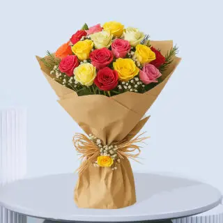 A vibrant bouquet of mixed garden roses in shades of red, yellow, pink, and orange with white baby's breath and green foliage, wrapped in brown paper and tied with a raffia bow and a small yellow rose.