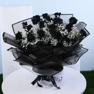 A vibrant bouquet of pink roses and white lilies wrapped in pink paper with a white ribbon presented on a white round table.