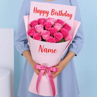 A bouquet of pink roses, wrapped in soft pink, featuring “Happy Birthday” at the top and a personalized name at the bottom. A pink ribbon is tied in a bow around the bouquet.