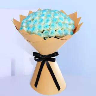 Bouquet of white roses with blue painted edges, wrapped in brown and tied with a black ribbon.