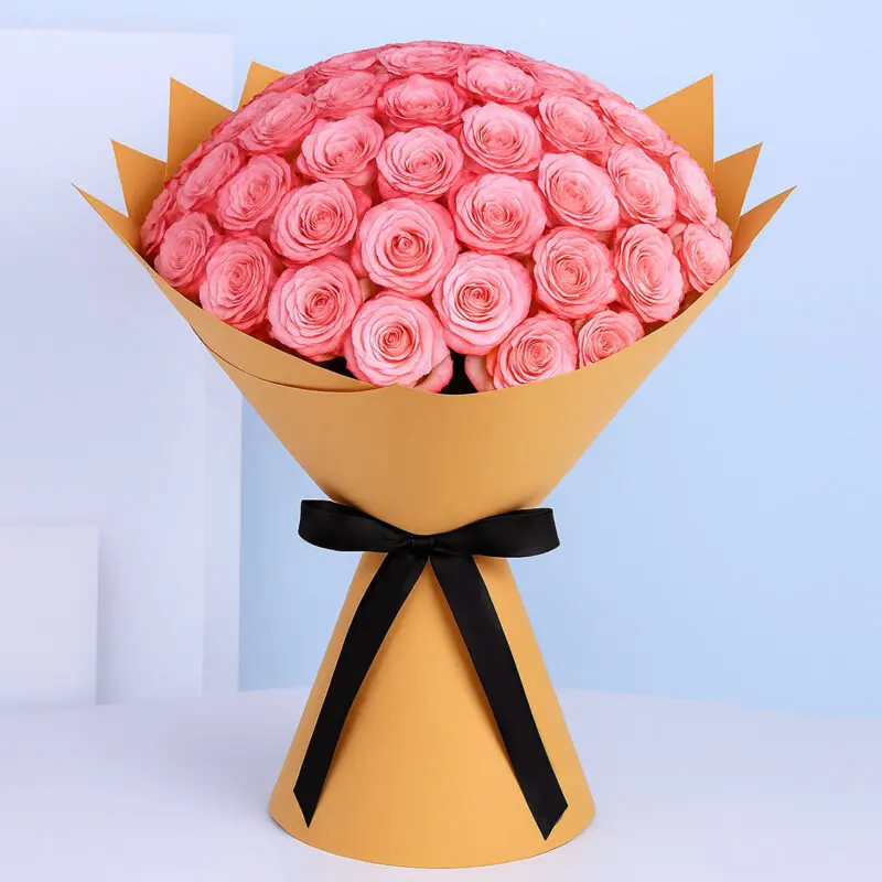 double-pink-roses-bouquet A large bouquet of fresh pink roses, tightly arranged and wrapped in brown and tied with a wide black ribbon.