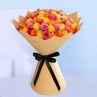 Bouquet of pink, yellow, and orange roses wrapped in brown tied with a black ribbon.