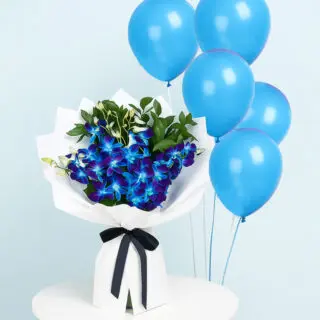 A striking bouquet of blue Dendrobium orchids with green leaves, wrapped in white and tied with a black ribbon with five light blue helium-filled balloons.