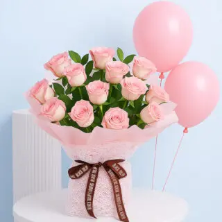 A beautiful bouquet of light pink roses with green leaves, wrapped in light pink, tied with a brown ribbon with three helium-filled pink balloons.