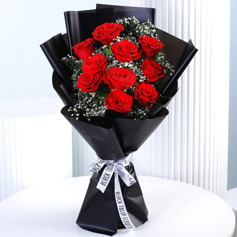 red-rose-black-wrap A bouquet of 10 vibrant red roses with white gypsophila (baby's breath) wrapped in black paper and tied with a black and white ribbon.